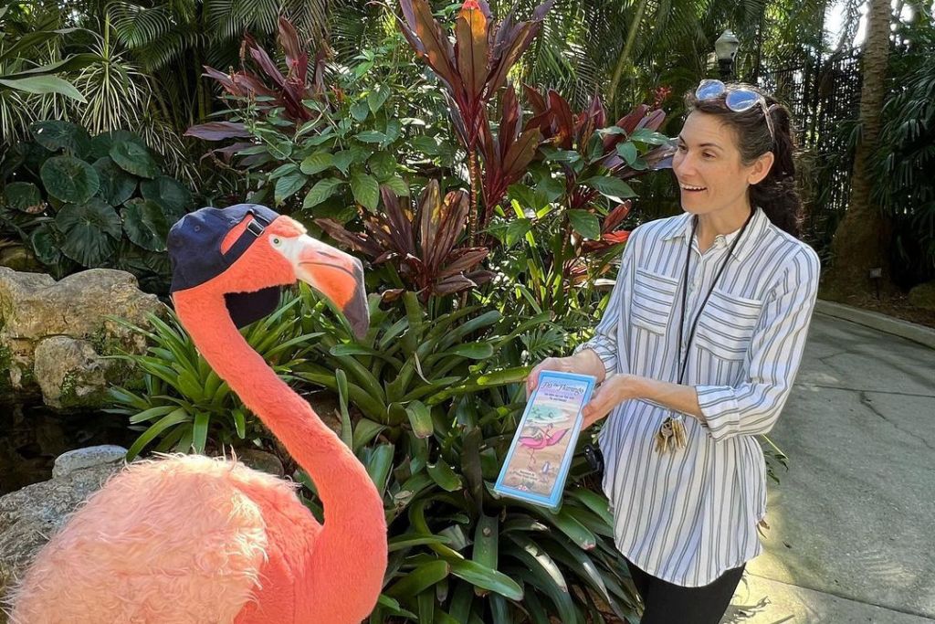 a lady showing flamingo a brochure in the garden